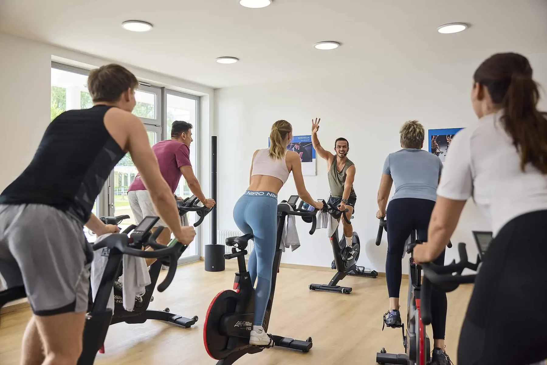 Gruppe auf Indoor-Cycling-Rädern in einem hellen Kursraum