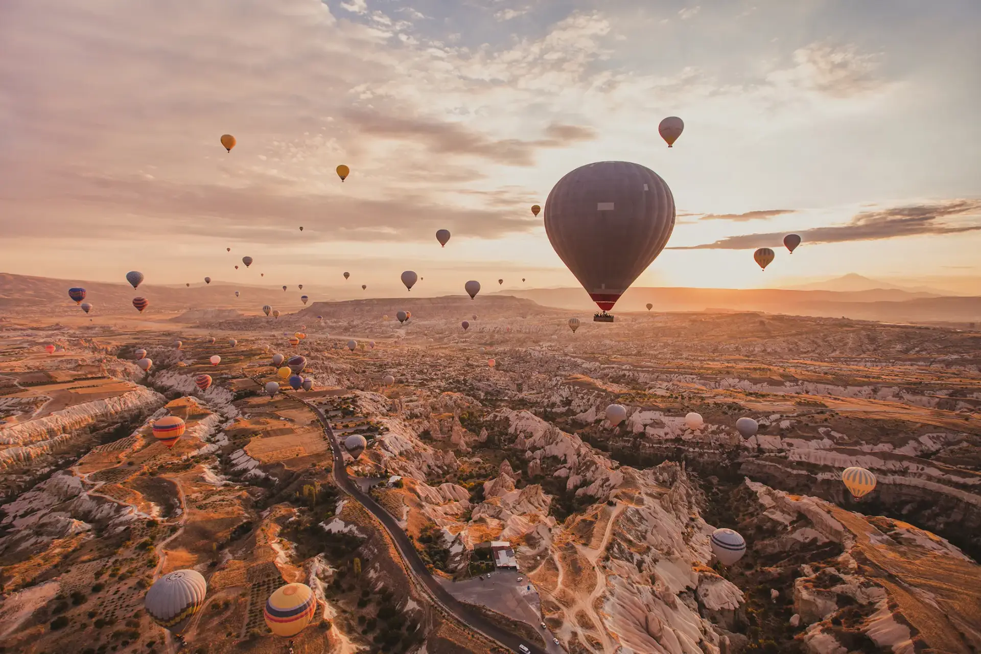 Zahlreiche Heißluftballons schweben im Morgenlicht über einer zerklüfteten Felslandschaft